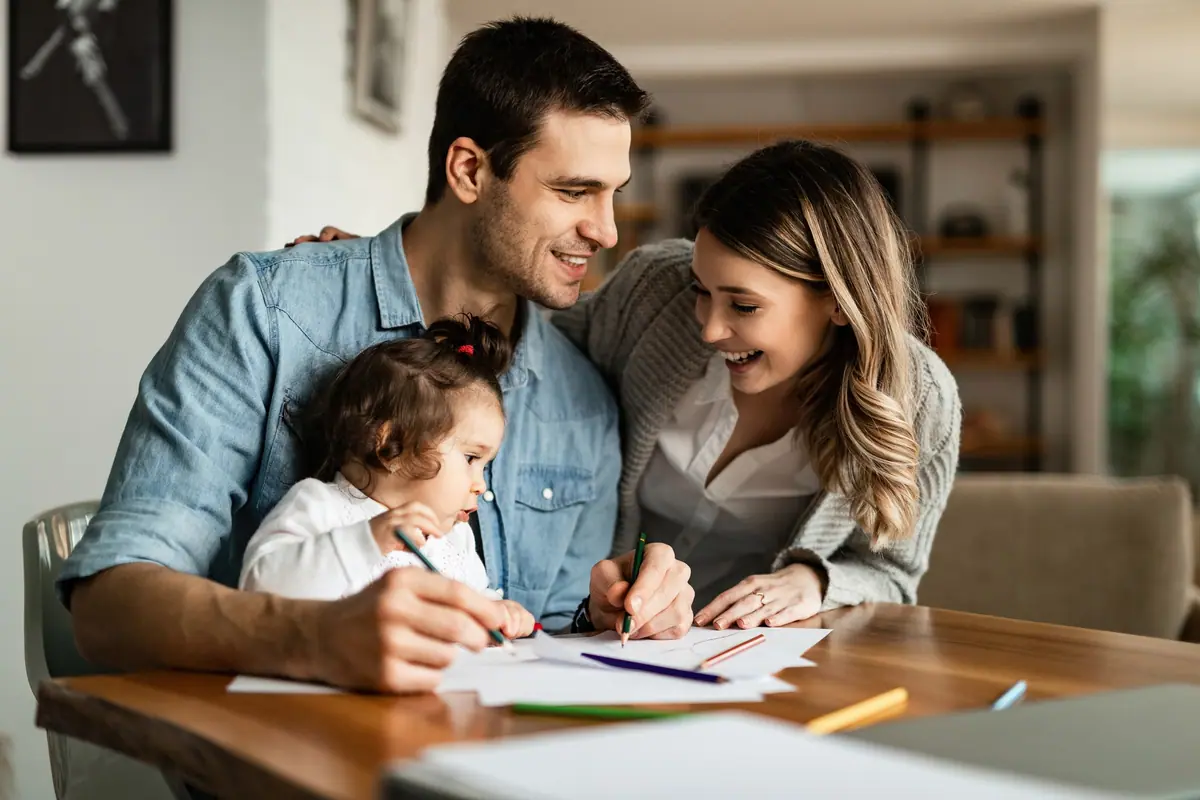 Parents and their young daughter drawing together at a table