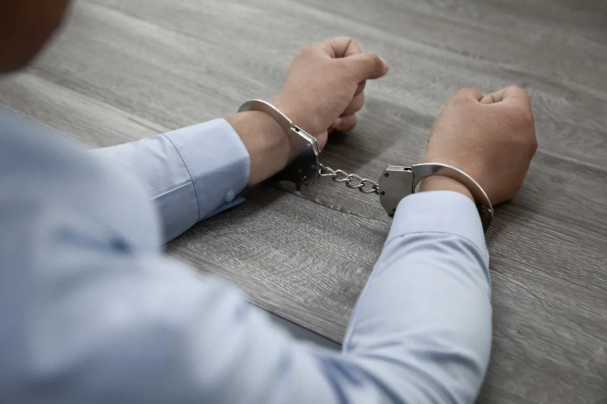 Person in handcuffs seated at a table