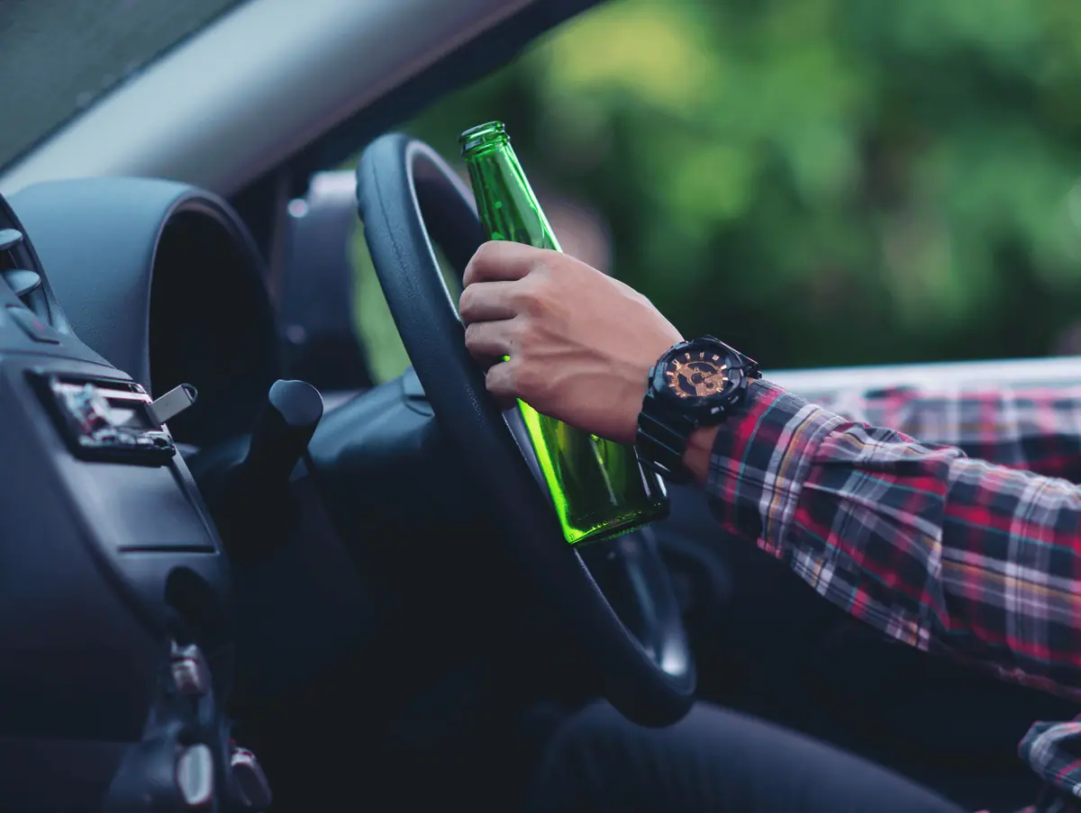 Driver holding a bottle behind the wheel